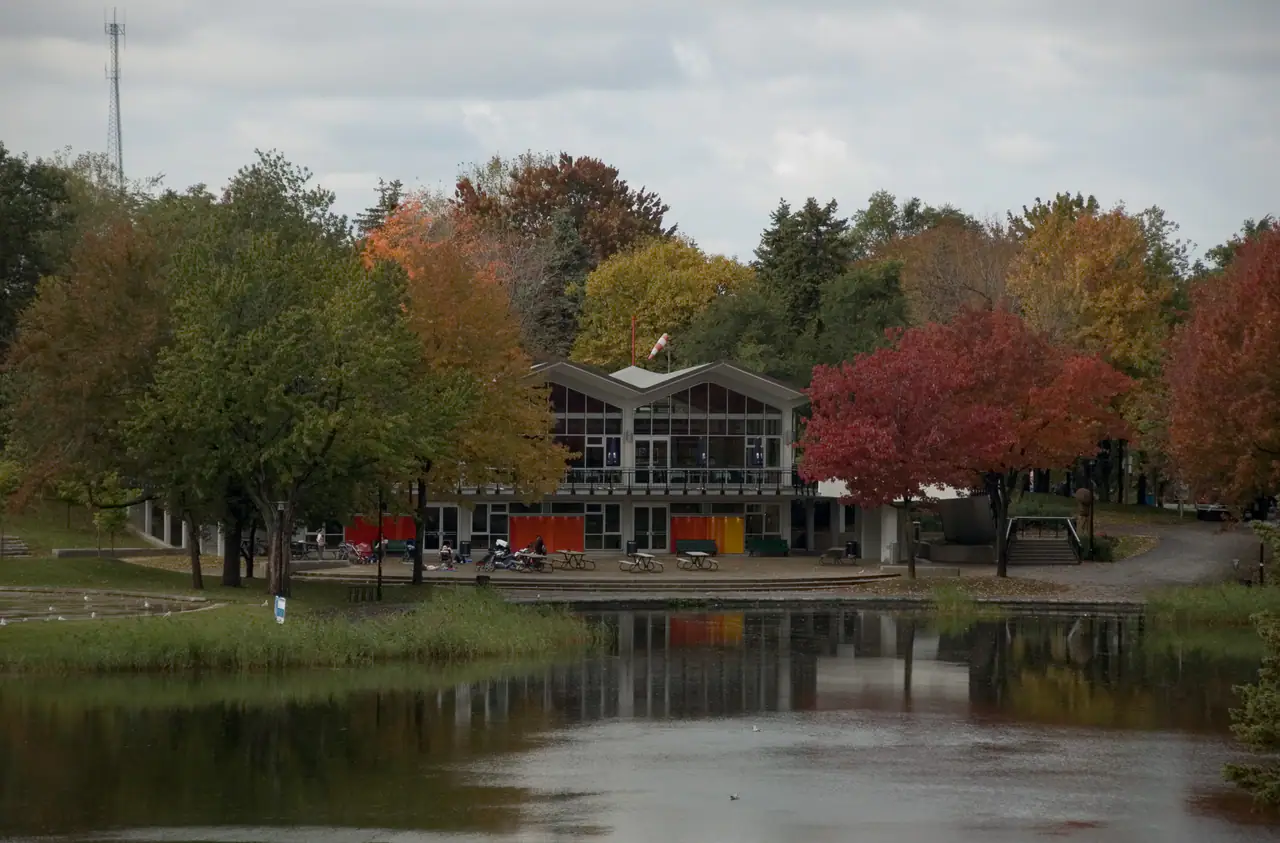The Beaver Lake pavilion on Mount Royal in autumn, framed by red and gold trees and reflected in the still water