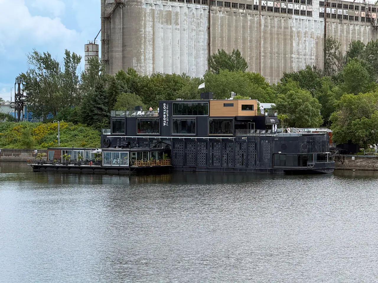 The black, container-clad Bota Bota spa ferry moored in the Old Port, with the concrete grain silos rising behind it
