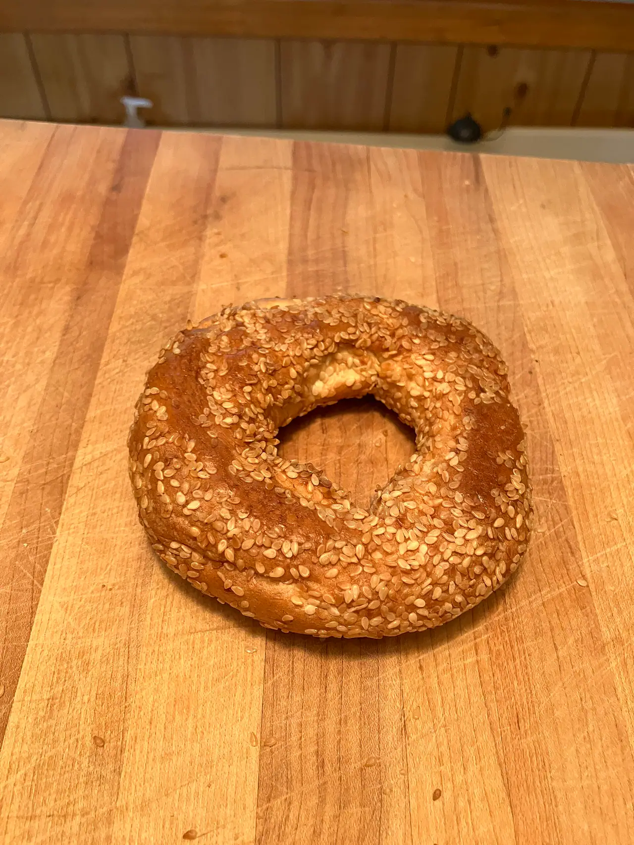 A sesame-crusted Montréal-style bagel from Fairmount Bagel resting on a worn wooden butcher-block counter