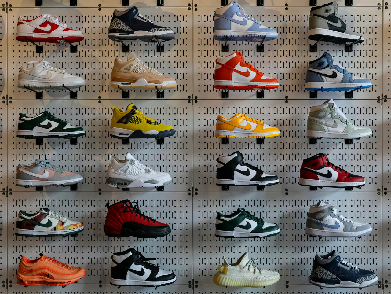 A wall of pegboard panels holding five rows of colourful Nike and Jordan-style sneakers in a store