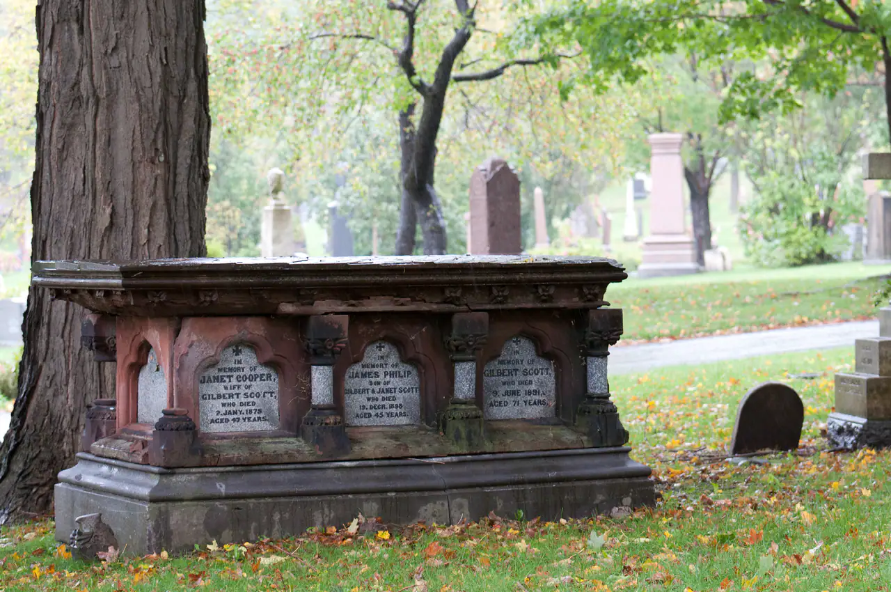 A nineteenth-century stone tomb under trees at Mount Royal Cemetery, fallen leaves on the grass